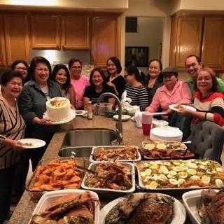A group of people gathered in a kitchen with a variety of dishes for a celebration.