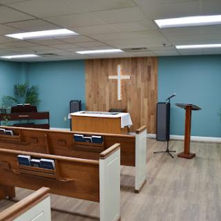 An interior view of a serene church setting with wooden benches and a focal cross.