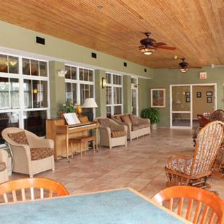 A spacious sunroom featuring comfortable seating, large windows, and a wooden ceiling with ceiling fans.