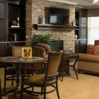 A cozy living room featuring a stone fireplace, a television, and comfortable seating arrangements.