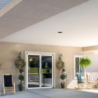 A cozy porch with chairs, potted plants, and a sliding glass door entrance.