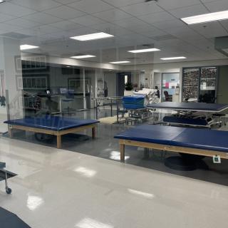 A spacious therapy room equipped with exercise tables and various rehabilitation equipment.