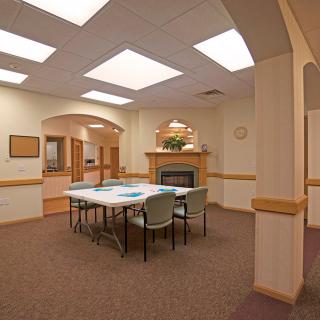 A well-lit conference room with a table and chairs arranged in the center.