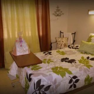 A cozy bedroom featuring a floral bedspread, bedside table, and soft lighting.