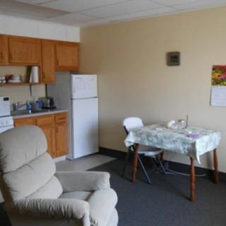 A cozy apartment interior featuring a small kitchen and dining area with a recliner.