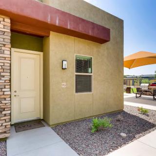 A modern residential entrance featuring a stylish door, landscaping, and outdoor seating.
