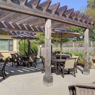 A cozy outdoor patio featuring a wooden pergola and ample seating.