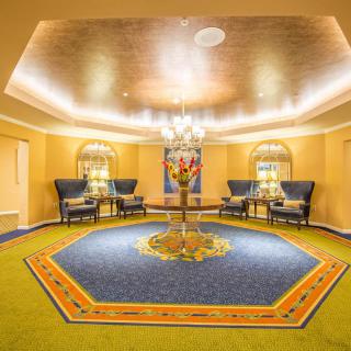 A luxurious lobby featuring a grand chandelier, elegant seating area, and a central table adorned with flowers.