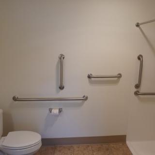 A bathroom with accessibility features including grab bars and a toilet.