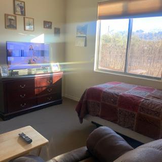 A cozy bedroom featuring a TV, comfortable bedding, and a view outside.