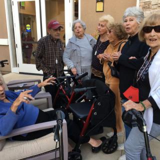A group of elderly individuals engaged in conversation outdoors.