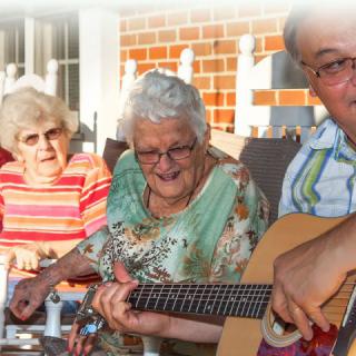 A group of seniors enjoying a musical gathering outdoors.