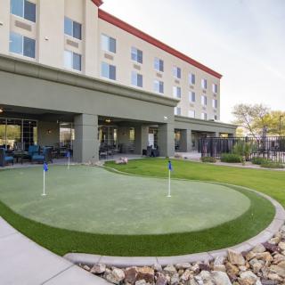 A hotel with an outdoor putting green surrounded by a landscaped lawn.