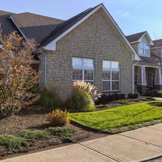 A suburban residential house with a well-maintained front yard and brick exterior.