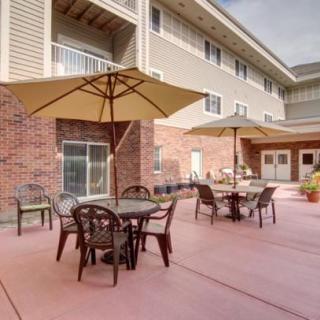 A spacious outdoor patio area with tables, chairs, and umbrellas in front of a building.