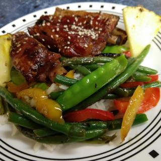 A delicious plate featuring steak, colorful vegetables including green beans and peppers, and a slice of pineapple.