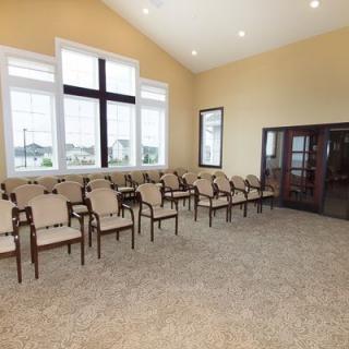 A spacious conference room with rows of chairs and large windows.