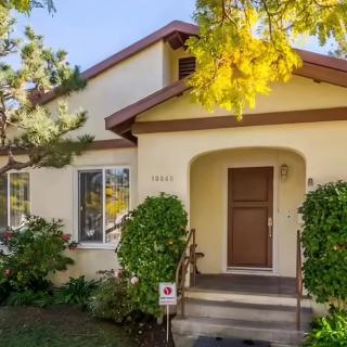 A charming residential house with a wooden front door, surrounded by greenery.