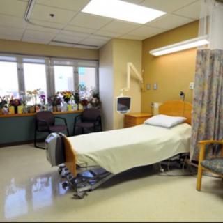 A clean and neatly arranged hospital room with a single patient bed.