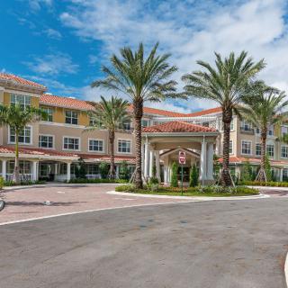 A resort-style building with palm trees in front and a clear blue sky.