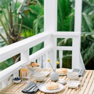 A serene breakfast setup on a balcony overlooking lush greenery.