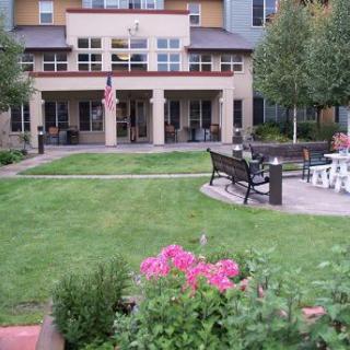 A well-maintained garden with benches and a flower bed in front of a building.