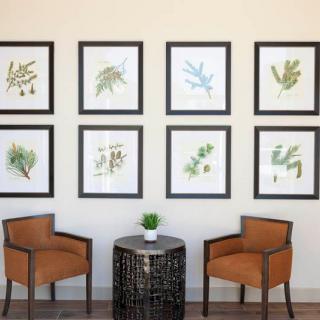 A cozy seating area featuring framed botanical prints, two orange chairs, and a small round table.