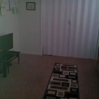 A minimalist living room with a TV and a patterned rug.