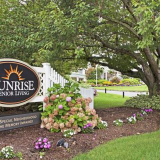 A scenic view of a landscaped garden with a sign reading 'Sunrise Senior Living'.
