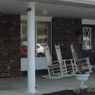 A cozy porch with white rocking chairs and a brick wall backdrop.
