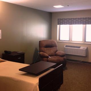 A cozy bedroom featuring a comfortable chair, bed, and large windows for natural light.