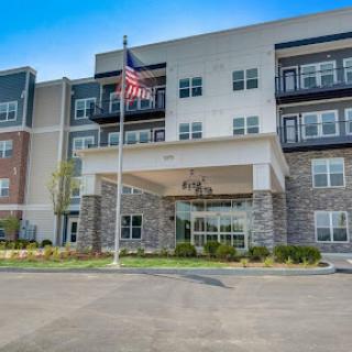 A modern multi-story building featuring a welcoming entrance and an American flag.