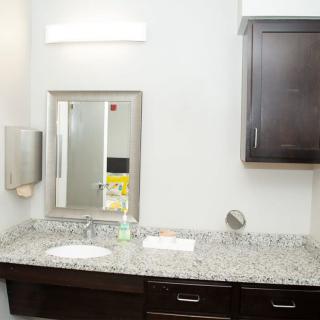 A clean bathroom with a granite countertop, mirror, and dark wood cabinets.