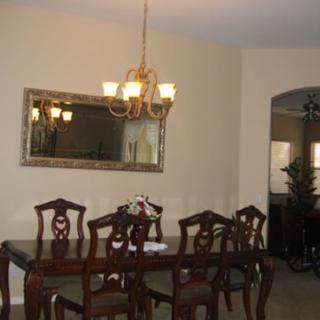 A dining room with a wooden table and chairs, adorned with a chandelier and wall mirror.