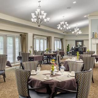 An elegant dining room with neatly arranged tables and chairs, adorned with chandeliers.