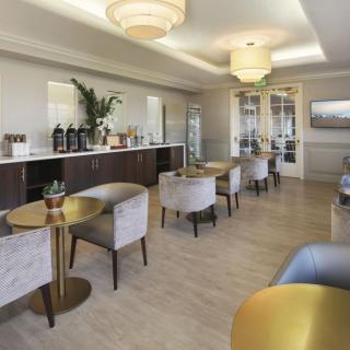 A modern and stylish lounge with comfortable seating, tables, and a coffee station.