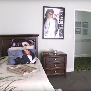 A bedroom featuring a bed with themed bedding and a large poster on the wall, complemented by a nightstand and decorative items.