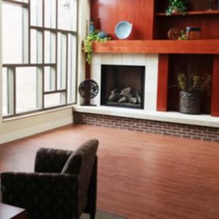 A modern living room with a fireplace, armchair, and decorative shelves.