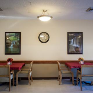 A cozy dining area with red tablecloths, wooden furniture, and wall decorations.