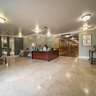 A spacious and modern reception area with a desk, chairs, and a hallway in the background.