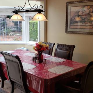 A cozy dining room with a table set for a meal, featuring a red tablecloth and a vase of flowers.