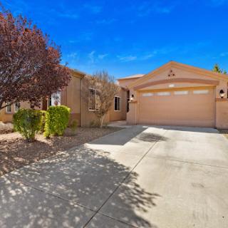 A beautiful residential home with a spacious garage and well-maintained landscape under a clear blue sky.