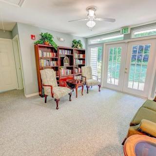 A cozy indoor lounge with comfortable chairs, bookshelves, and natural lighting.
