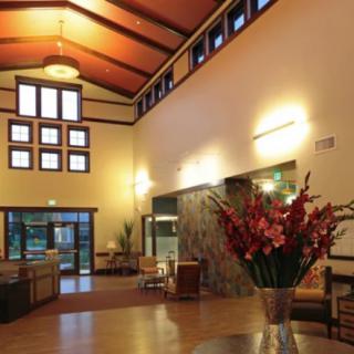 A modern and spacious lobby with high ceilings, stylish lighting, and floral arrangements.