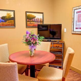 A cozy dining area with a round table, floral centerpiece, and a TV in the corner.