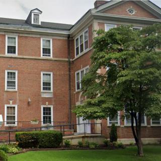 A brick building with trees and grass in the foreground.
