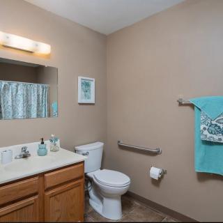 A well-organized bathroom featuring a sink, mirror, toilet, and teal towel accents.