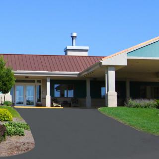 A building with a driveway and landscaped surroundings under a clear blue sky.