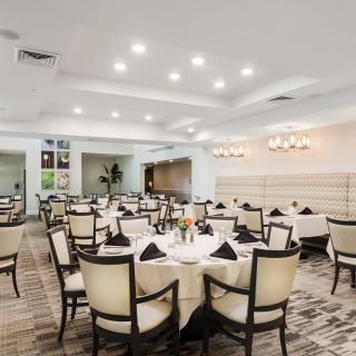 An elegant dining area set for guests, featuring neatly arranged tables and chairs under soft lighting.