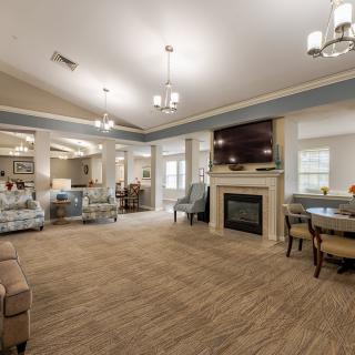 A spacious and modern living room featuring a central fireplace, elegant furniture, and ceiling lights.